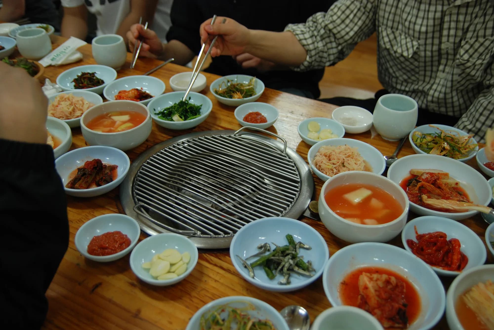 Meat cooking on a Korean barbecue grill with side dishes (illustrative photo)